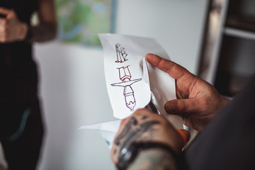Male tattoo artist shows a sketch of the future tattoo client