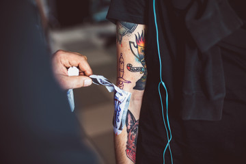 Master tattoo artist showing process of transfer tattoo sketch on a hand using special thermal paper.