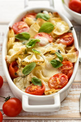 Casserole with farfalle pasta, cherry tomato, mozzarella cheese and herbs
