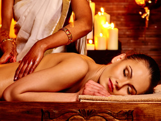 Young woman having oil Ayurveda spa treatment. Lighting candles.