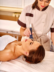Obraz na płótnie Canvas Young woman gets rejuvenating electric ultrusound facial massage at beauty salon. 