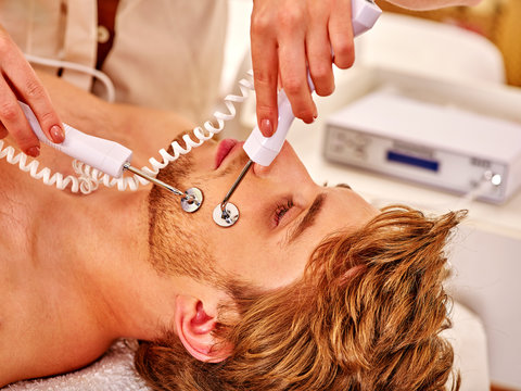 Man gets revitalizing electric facial peeling hydradermie at beauty salon. 