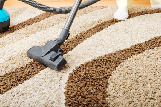 Senior woman vacuuming carpet at home