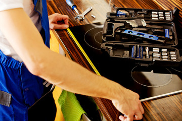 Young repair man measuring kitchen cabinet