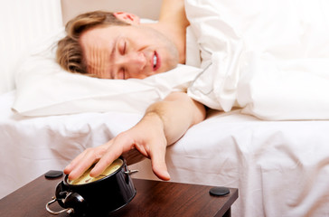 Obraz na płótnie Canvas Man trying to sleep, when alarm clock ringing