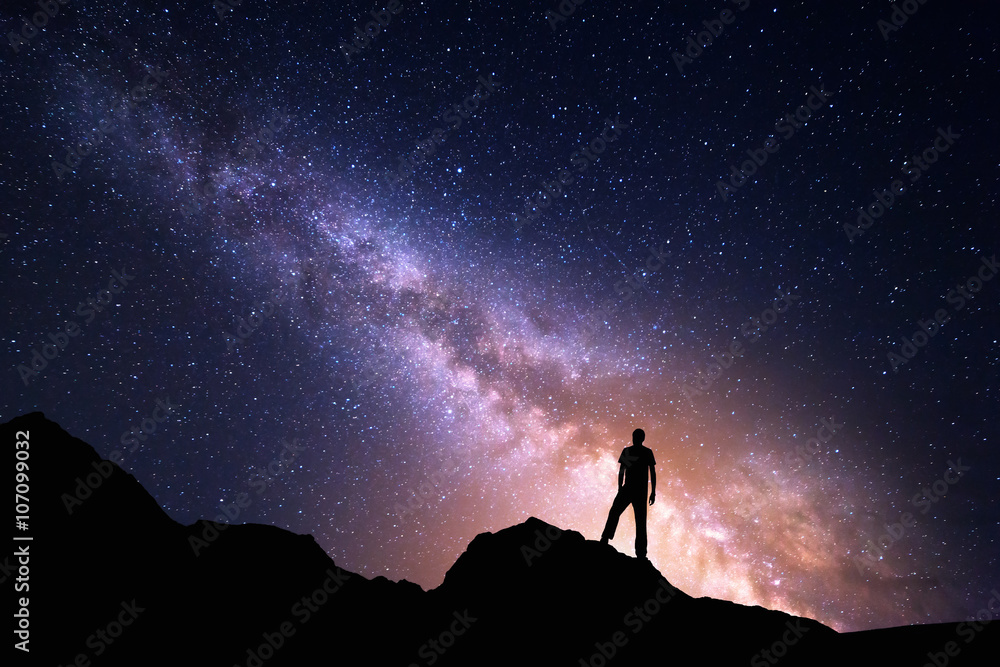 Wall mural landscape with milky way. night sky with stars and silhouette of a happy man on the rock. beautiful 
