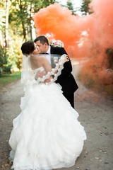 Elegant young happy wedding couple is sitting at green grass on