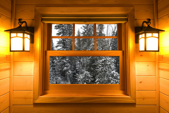 Inside View Snow Covered Trees In A Cedar Cabin Window With Lights On