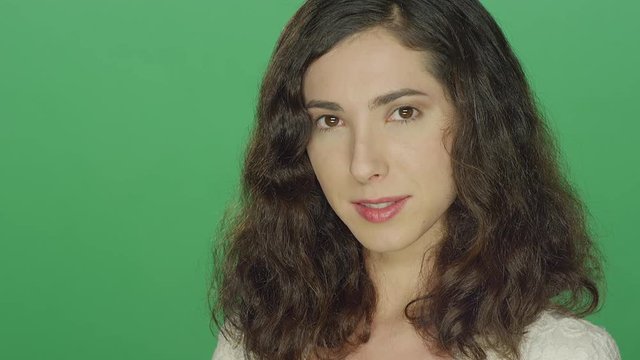 Young brunette woman smiling, on a green screen studio background 