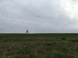 Man running along top of river embankment