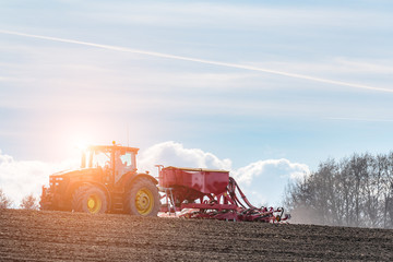 Sunset above the tractor harrowing the field