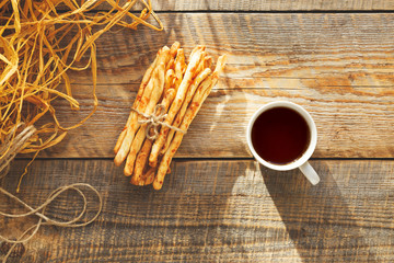 Heap of bread sticks with tea on wooden table