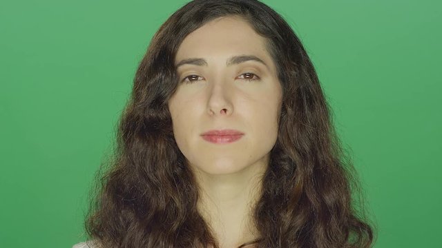 Young brunette woman staring, on a green screen studio background