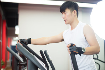Naklejka na ściany i meble young handsome asian man works out in modern gym