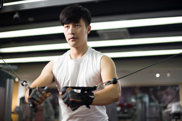 Fototapeta na wymiar young handsome asian man works out in modern gym