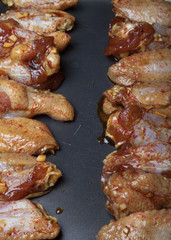 Marinated chicken wings on a black pan. Selective focus