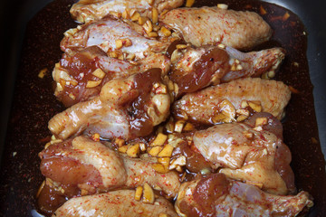 Marinated chicken wings on a black pan. Selective focus