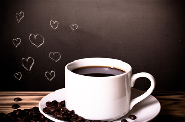 Romantic theme on a chalkboard behind a wooden table with cup of