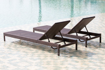 Swimming pool and two deck chairs, close up
