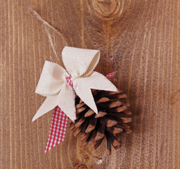 Pine cone with bow./Pine cone on a wooden background texture.