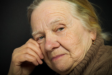 Portrait of elderly woman on dark background. Toned