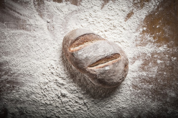 Naklejka premium Fresh home bread fell in a heap of flour. Toned