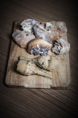 Fresh home bread and marinated artichokes on the light wooden cu
