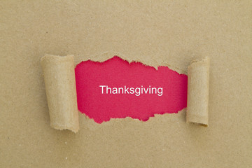 Thanksgiving word written under torn paper.