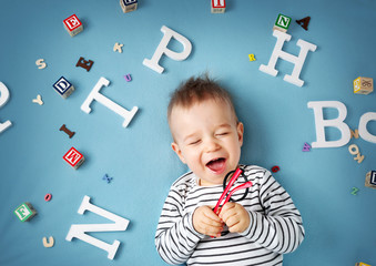 One year old child lying with spectacles and letters