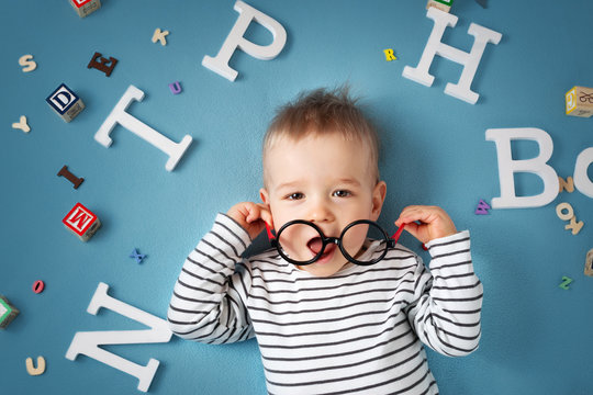 One year old child lying with spectacles and letters