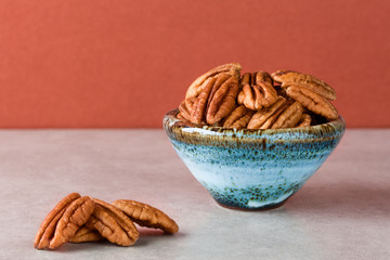 Pecans on marble surface and in ceramic bowl with brown background. Copy space, shallow depth of field