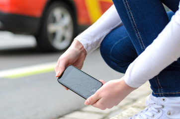Young woman picking up her shattered mobile