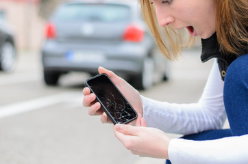 Young woman picking up her smashed mobile