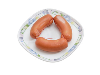 Three uncooked sausages on a dish on a light background