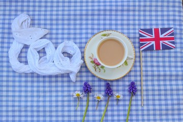 Traditional milky tea served in a bone china cup and saucer with a Union Jack flag and wild flowers 