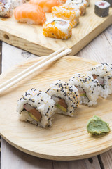 Different Sushi rolls,wasabi and ginger on a plate on wooden bac