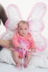 2 months old baby girl held on mother's arms with wings fairy