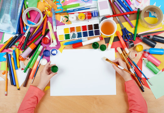 Child drawing top view. Artwork workplace with creative accessories. Flat lay art tools for painting.