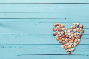 Background with heart made of seashells on blue painted wooden p