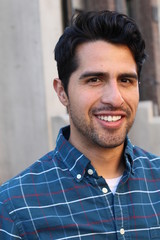 Obraz premium Young and attractive latino male smiling in the city
