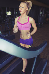 Fototapeta premium Fitness girl running on treadmill
