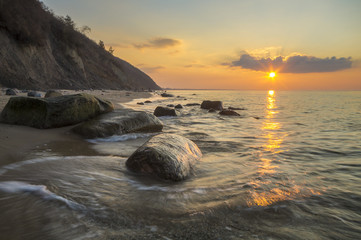 Klif i plaża morska w świetle zachodzącego słońca