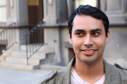 Closeup Portrait Of A Happy Hispanic/Spanish Man Looking To Left. Against Urban Background.