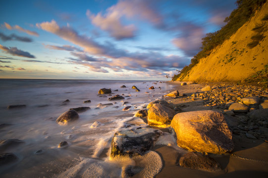 Fototapeta Klif i plaża morska w świetle zachodzącego słońca