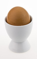 egg in white egg cup, isolated on white.