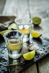 Gold tequila shots on rustic wood background
