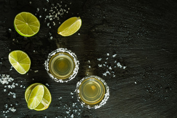Gold tequila shots on rustic wood background