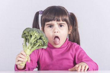 Little girl making a funny face refusing to eat her vegetables