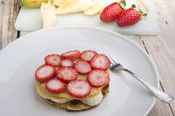 Stack of golden pancakes with strawberries, banana,