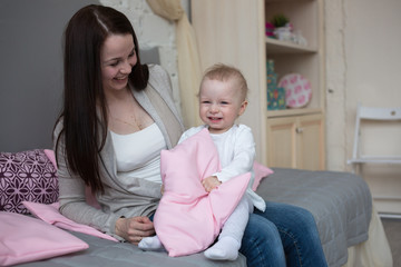 Funny playful mum with baby toddler at home